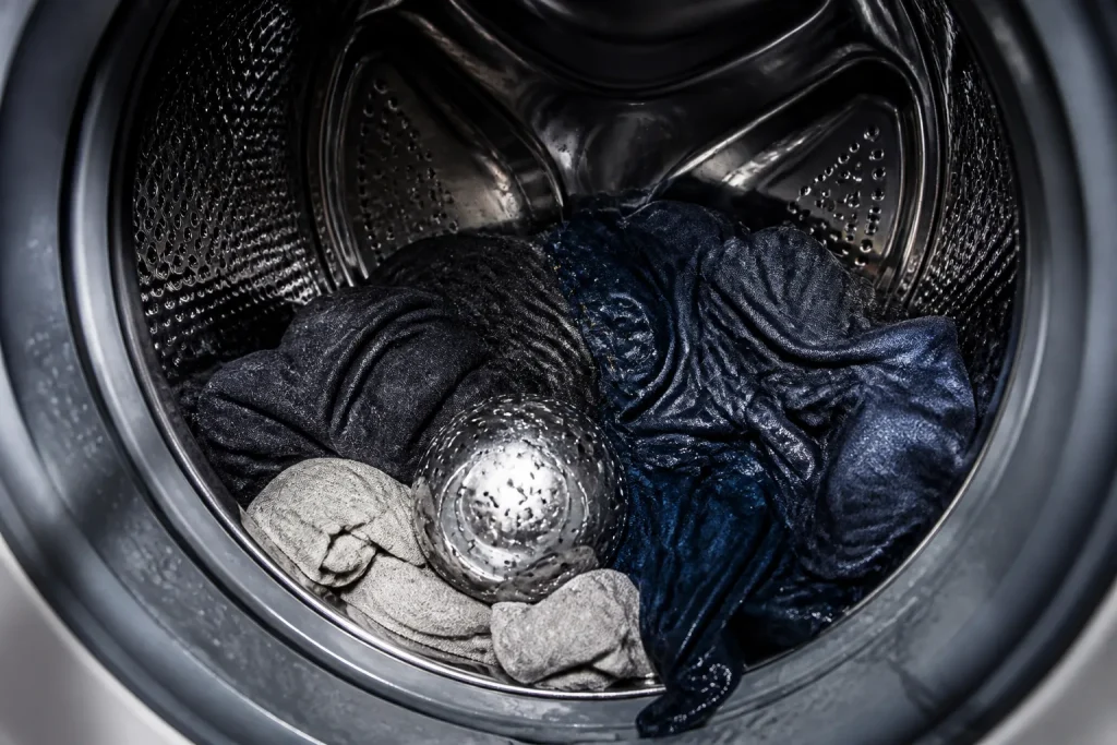Boule aluminium dans tambour lave-linge avec vetements mouilles