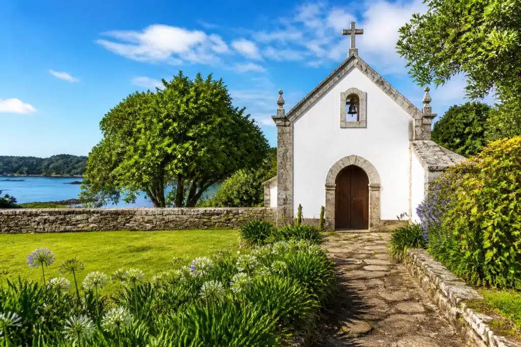 Petite chapelle en pierre avec murs blancs et jardins verts