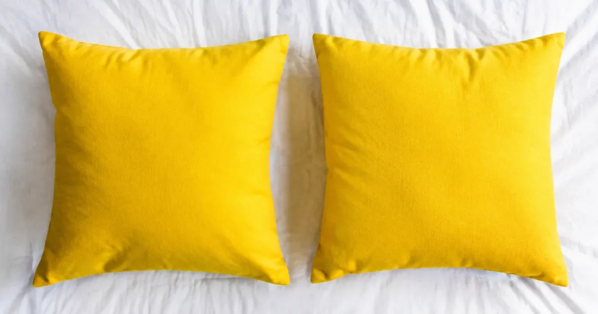 Deux coussins jaunes alignes surface textile blanche