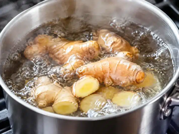 Racine de gingembre frais mijotant dans eau bouillante, casserole métallique