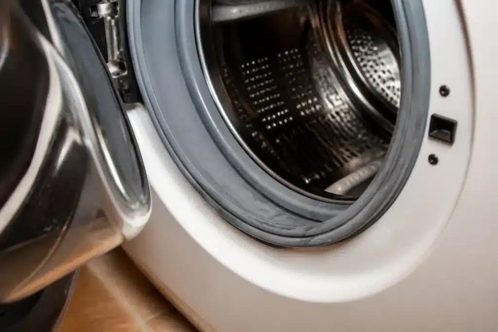 Hublot de lave-linge entrouvert avec joint humide visible