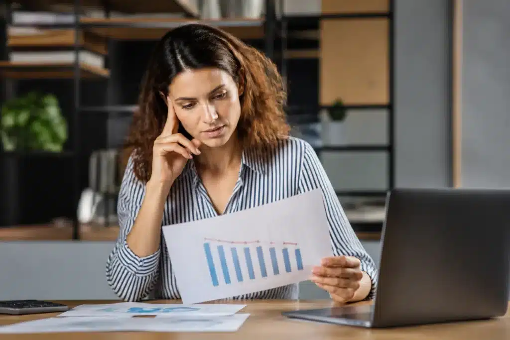 Femme consultant documents professionnels, graphique salaires en baisse visible