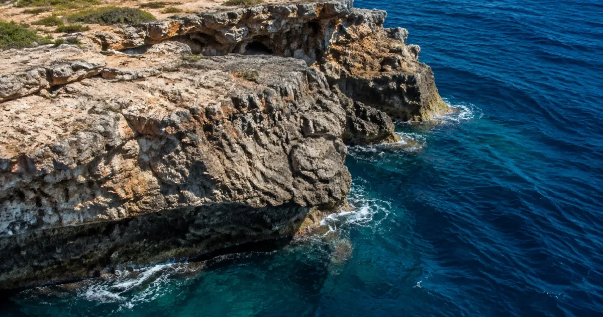 Plateau rocheux submerge plongeant dans ocean bleu sombre