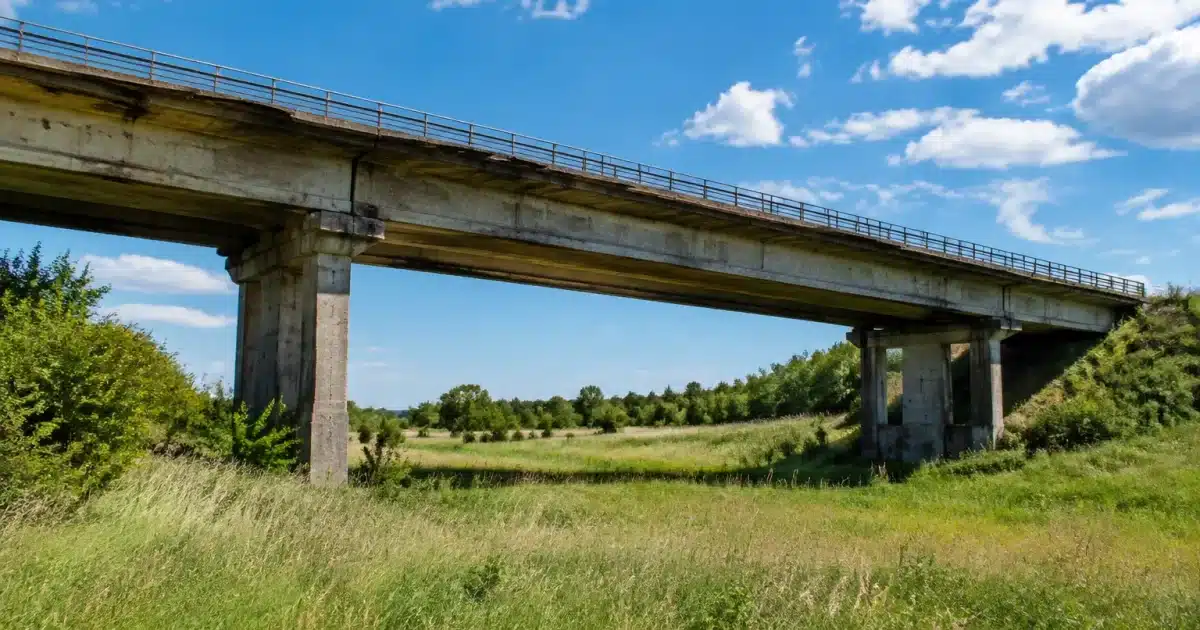 Pont de béton désaffecté enjambant un champ vide et herbeux