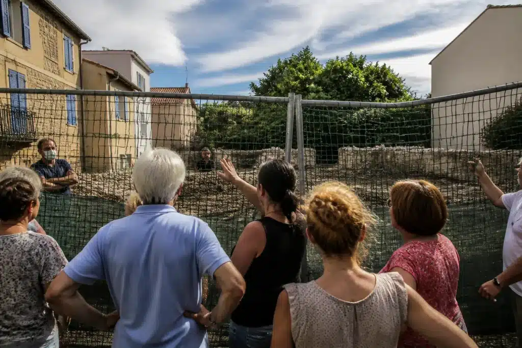 Panneau de chantier barricadé devant bâtiments avec habitants protestataires.