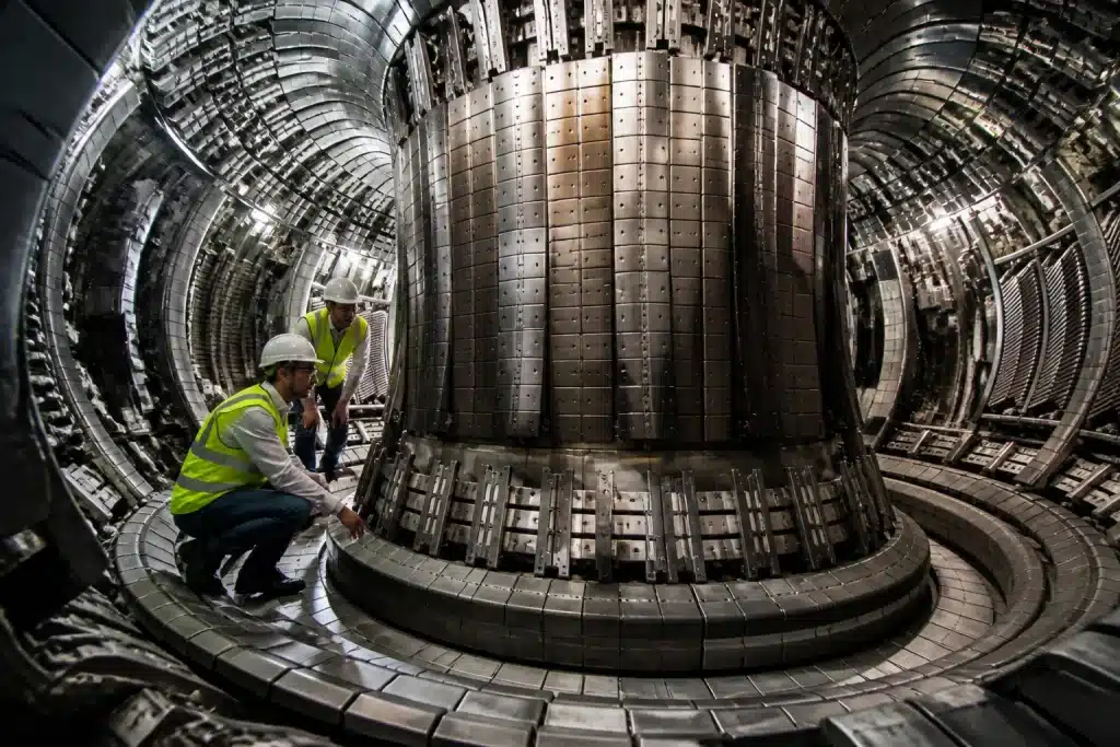 Ingénieurs inspectant chambre vide tokamak avec composants